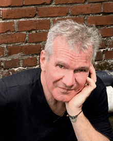 a man with gray hair and a bracelet on his wrist