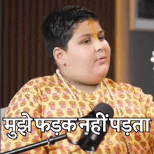 a boy in a yellow shirt is sitting in front of a microphone with a caption in a language other than english .