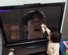 a baby wipes his face in front of a panasonic television