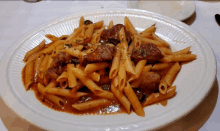 a plate of pasta with meat and sauce is on a table