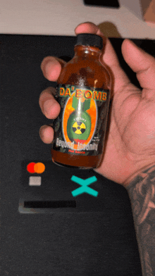 a person holding a bottle of day bomb hot sauce