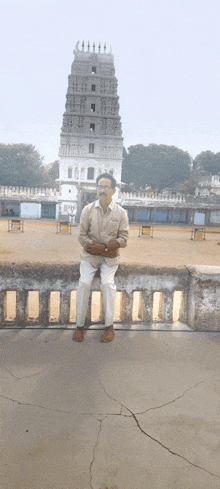 a man sits on a railing in front of a tall building