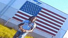 a man stands in front of an american flag and a building that says ' a & r ' on it