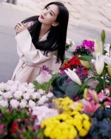 a woman kneeling in front of a bunch of flowers