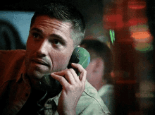 a man talking on a green telephone with a blurry background