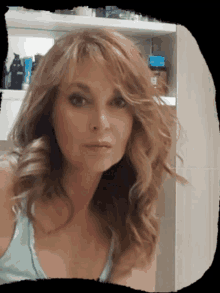 a woman in a blue tank top is standing in front of a shelf