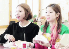 two girls are sitting at a table with a mcdonald 's cup on it .