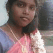 a close up of a woman wearing a pink saree and a blue shirt .