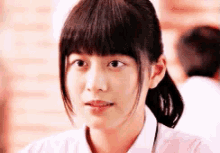 a close up of a girl 's face with a ponytail and bangs .