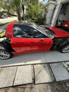 a damaged red sports car is parked in front of a garage with a sign that says ' gatorade '