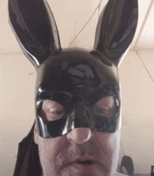 a man is wearing a black bunny mask