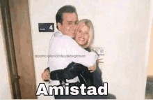 a man is carrying a woman in his arms in a room with the word amistad .