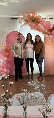 a group of people standing in front of a wall of balloons