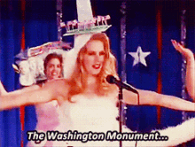 a woman in a white dress stands in front of a microphone with the words the washington monument above her