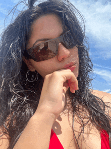 a woman in a red bikini is wearing sunglasses and earrings