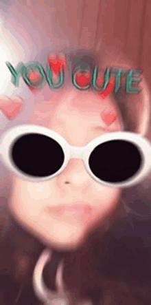 a girl wearing sunglasses with the words you cute on her head