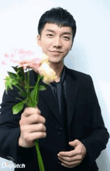 a man in a suit is holding a bouquet of flowers in his hands .