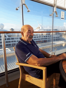 a man wearing a lotto shirt sits in a chair on a balcony