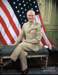 a man in a military uniform is sitting in front of an american flag