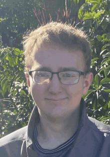 a young man wearing glasses and a striped shirt smiles for the camera