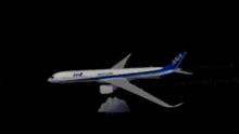 a blue and white ana airplane is flying in the dark