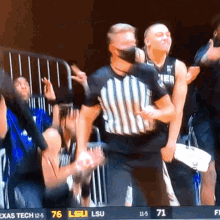 a referee wearing a face mask stands in front of a crowd during a basketball game between lsu and texas tech