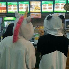 two people wearing unicorn and panda costumes are looking at a menu