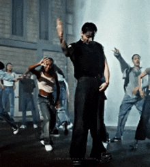 a group of people are dancing in front of a brick wall