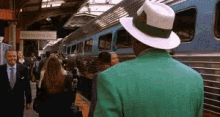 a man in a green jacket and white hat is standing in front of a sign that says washington dc