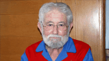 a man with glasses and a beard is wearing a red blue and white shirt