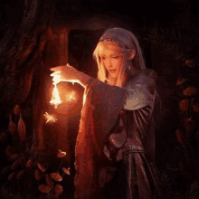 a woman in a long dress is holding a candle in her hand and a fairy is flying around her .