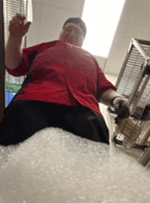 a man in a red shirt is standing on top of a pile of bubble wrap .