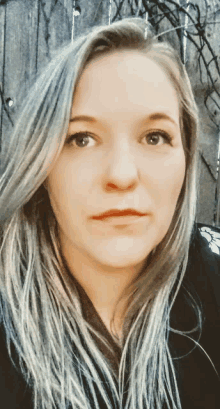 a close up of a woman 's face with a fence behind her