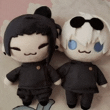 a couple of stuffed dolls sitting next to each other on a bed