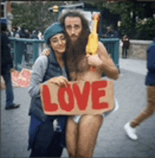 a man holding a sign that says love is being held by a woman