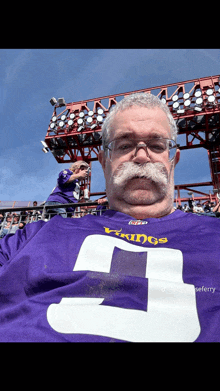 a man with a mustache and glasses is wearing a vikings jersey