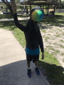 a person wearing a hoodie with a colorful ball in front of their face