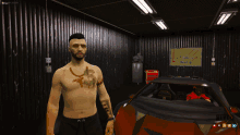 a shirtless man with a tattoo on his chest stands in a garage next to a car