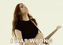 a woman singing and playing a guitar with the words " i was wrong " below her