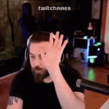 a man with a beard is wearing headphones and waving his hand in a video game .