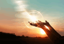 a person 's hands are reaching up towards the sun at sunset