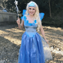 a woman in a blue dress is holding a wand with a star on it