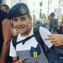 a young boy wearing a black beret and a medal with the word rin on it