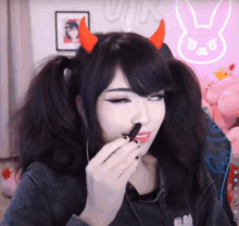 a girl with devil horns on her head is eating a cookie