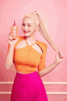 a woman in a pink dress is holding a bottle of shampoo