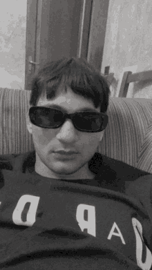 a black and white photo of a man wearing sunglasses and a shirt that says a