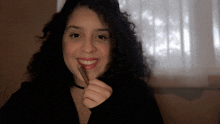 a woman with curly hair is holding a cigar in her hand