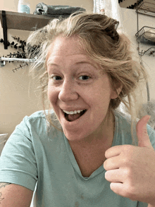 a woman in a blue shirt gives a thumbs up sign