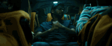 a man in a blue shirt is sitting in a dark room with other people