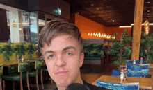 a young man is sitting in a restaurant with tables and chairs